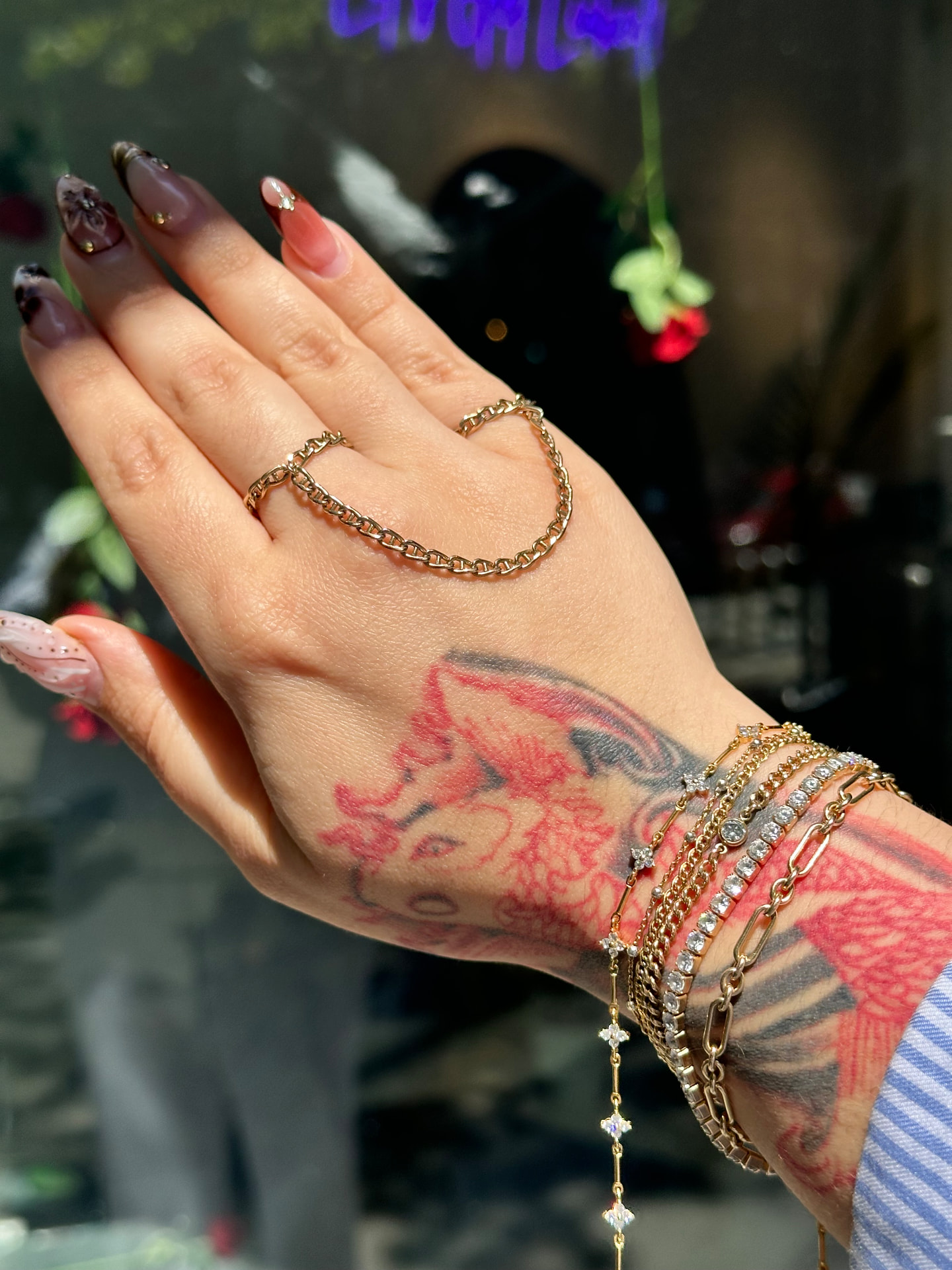 Stacked gold permanent bracelets on tattooed wrist